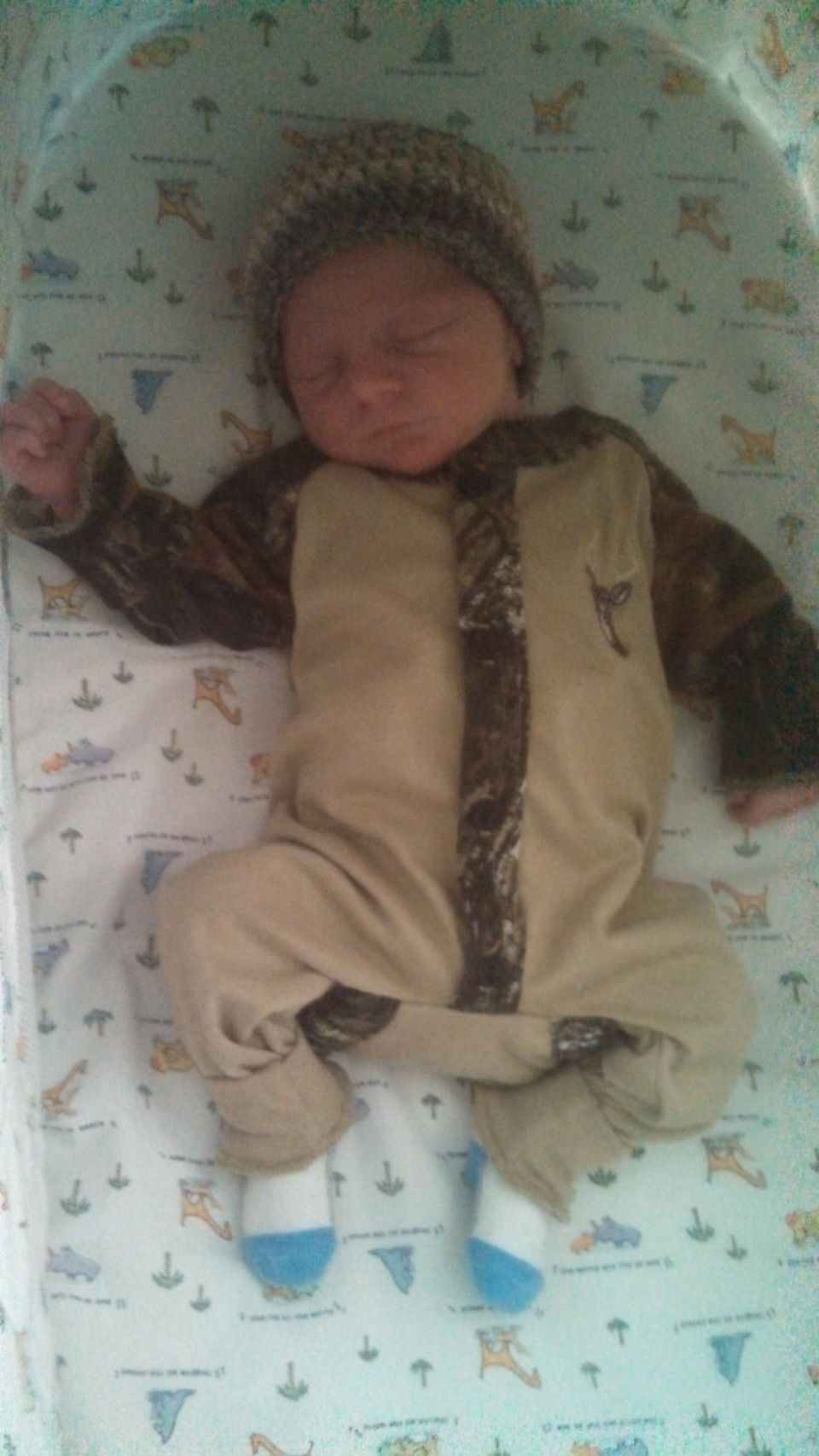 Baby sleeping in a crib wearing a camouflage outfit and a knit hat