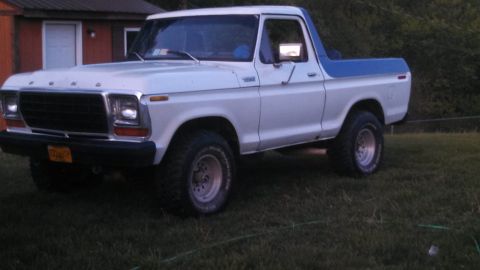 1979 Ford Bronco - This two-tone Ford Bronco sits on a grassy area next to a building.