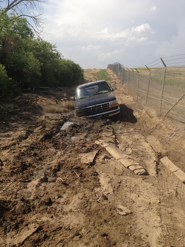 1995 Ford Bronco stuck in mud next to a fence
