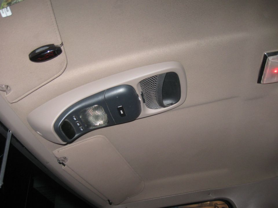 Overhead console with light, switch, and speaker grille in a vehicle interior
