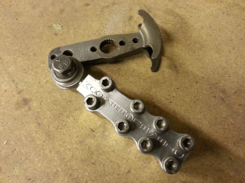 Metal tool with hex bolts and a toothed gear. Text reads 'ZOOMER' on one part