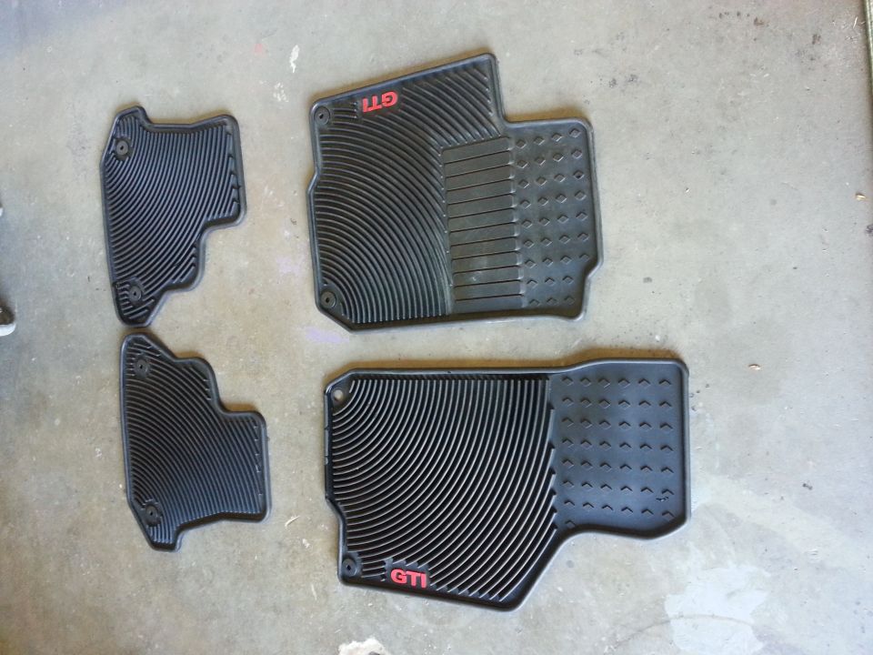 Four black rubber car floor mats with red GTI logos
