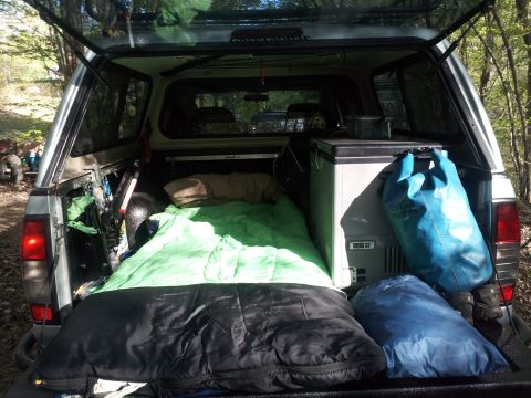 2003 Nissan Frontier - The bed of a silver Nissan Frontier is outfitted for camping with sleeping bags and a portable refrigerator.