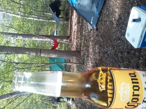2003 Nissan Frontier - A beer bottle is in the foreground of a campsite scene with tents and trees.