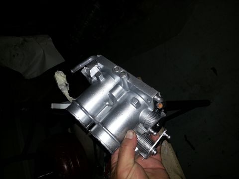 1994 Ford Bronco - A person is holding a silver throttle body, likely for engine repair or upgrade.