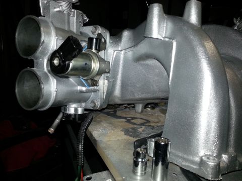 1994 Ford Bronco - Close-up of a silver throttle body and intake manifold assembly, with tools nearby.