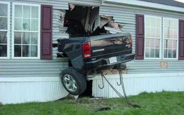 Dark Dodge 4x4 pickup crashed tail-first through the siding wall of a house