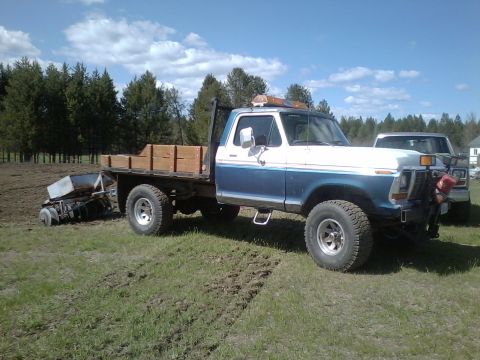1973 Ford F-250 - This 1973 Ford F-250 flatbed truck is parked in a field with a planter nearby.