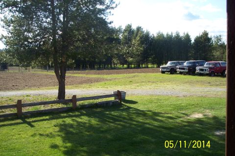1973 Ford F-250 - Several trucks are parked in a rural setting with a field and trees visible.