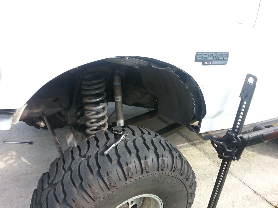 White 1992 Ford Bronco XLT front suspension with coil spring and shock absorber visible