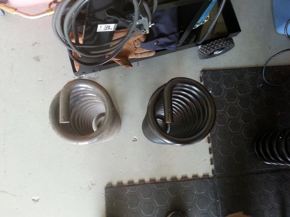 Two coil springs sit on a garage floor next to a toolbox with welding cables