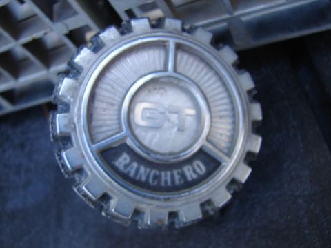 1973 Ford Ranchero - A close-up of a worn "RANCHERO GT" hubcap, detached from any vehicle.