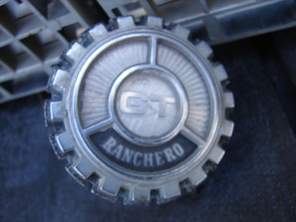 Chrome hubcap with "GT" and "RANCHERO" text, showing wear and damage