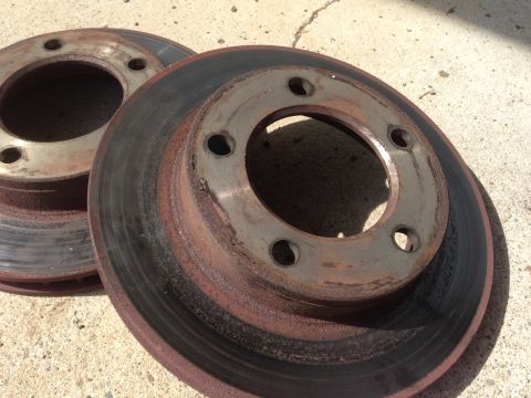 1990 Ford Bronco - Stack of used brake rotors showing significant rust and wear.