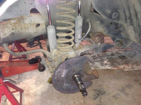 1990 Ford Bronco - The vehicle's front suspension and brake components are shown, with the rotor and hub assembly exposed.