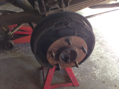1990 Ford Bronco - Close-up view of a vehicle's rear drum brake assembly, supported by red jack stands.