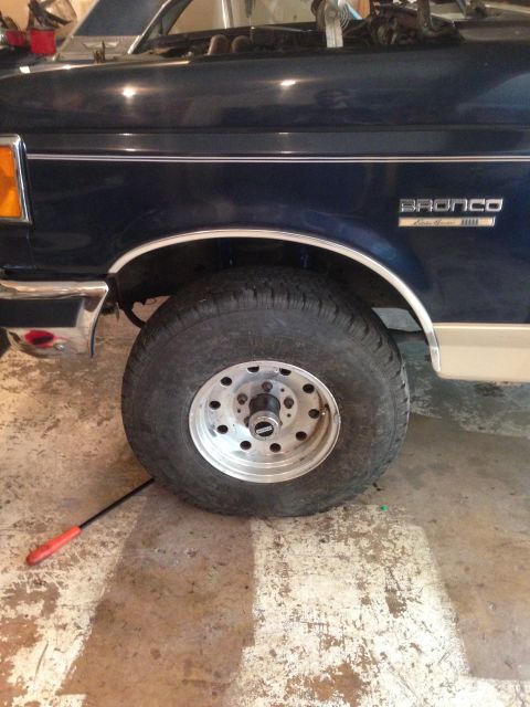 1990 Ford Bronco - The side view of a dark blue Ford Bronco shows its chrome trim and a silver wheel, confirming the 1990 model year.