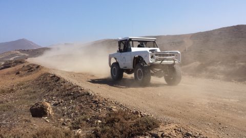 1996 Ford Bronco - Modified Ford Bronco races on a dusty desert trail, kicking up a large plume of dust.