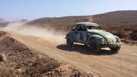 1996 Ford Bronco - A green 1974 Volkswagen Beetle, number 67, kicks up dust on a dirt road during a rally race.