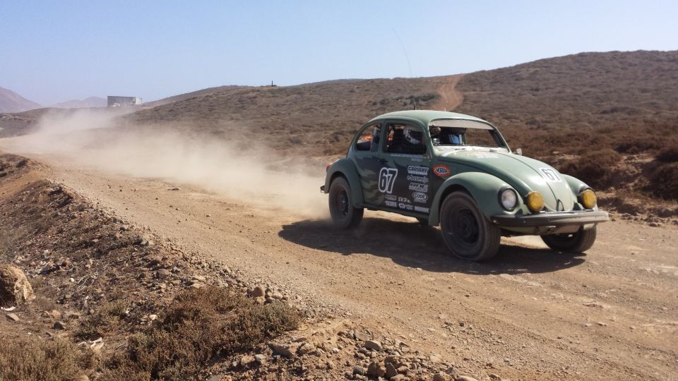 Green 1974 Volkswagen Beetle rally car with number 67 on dusty road