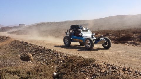 1996 Ford Bronco - Off-road buggy navigates a dusty desert track under a clear blue sky.