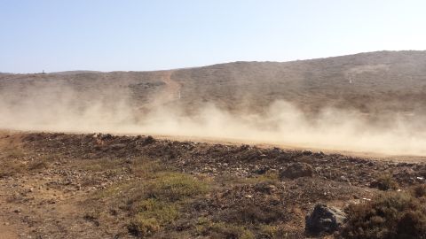 1996 Ford Bronco - Off-road vehicle creates a large dust cloud on a dry, hilly terrain.