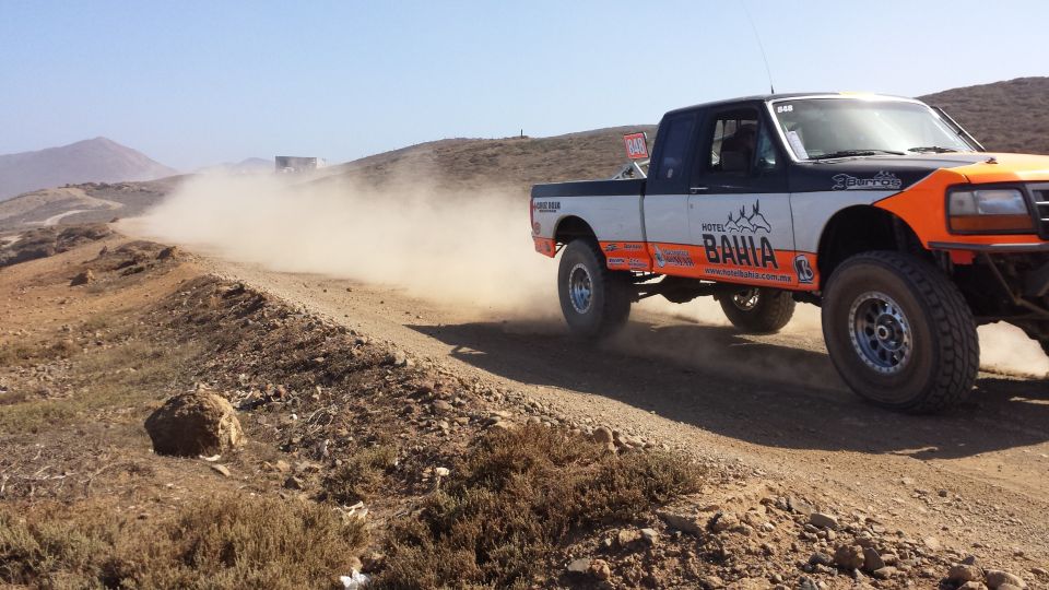 1996 Ford F-150 pickup truck racing off-road, kicking up dust. It has 'HOTEL BAHIA' graphics
