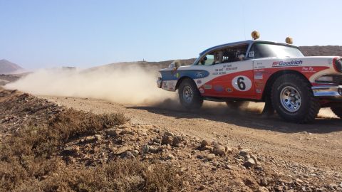 1996 Ford Bronco - A classic 1957 Ford Fairlane 500, modified for rally racing, speeds across a dusty off-road course.