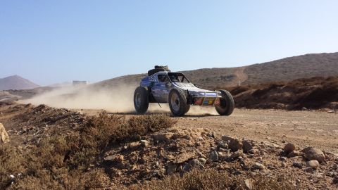 1996 Ford Bronco - An off-road buggy races down a dusty track under a clear blue sky.