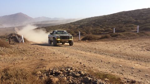 1996 Ford Bronco - A pickup truck kicks up dust as it races along a desert road.