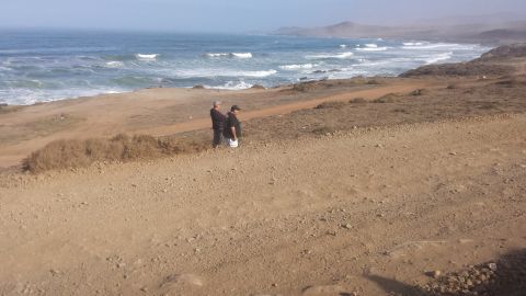 1996 Ford Bronco - Coastal landscape with two individuals observing the waves crashing on the shore.