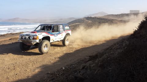 1996 Ford Bronco - A 1996 Ford Bronco competes in an off-road race, kicking up a cloud of dust on a coastal dirt track.