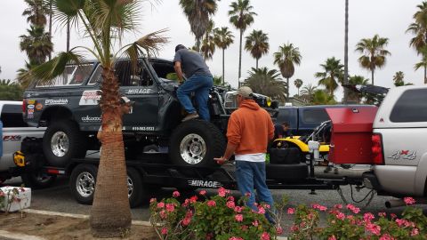 1996 Ford Bronco - Two men work on a lifted 1996 Ford Bronco loaded onto a trailer.