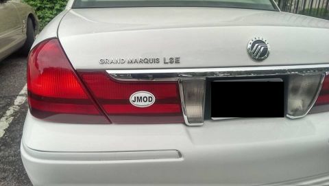 2000 Mercury Grand Marquis - Rear view of a white 2000 Mercury Grand Marquis, showing badging and a JMOD sticker.