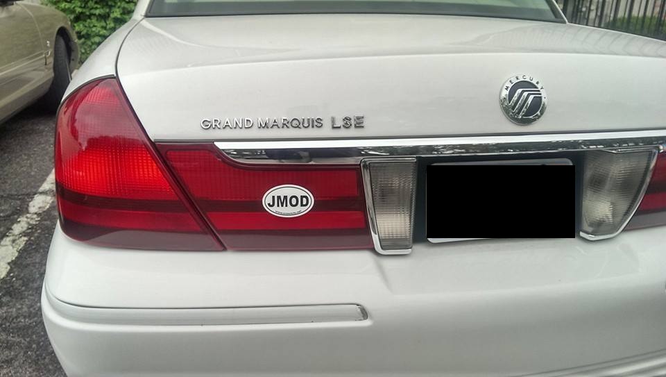 Rear of a white 2000 Mercury Grand Marquis with 'GRAND MARQUIS LSE' badging and a 'JMOD' sticker