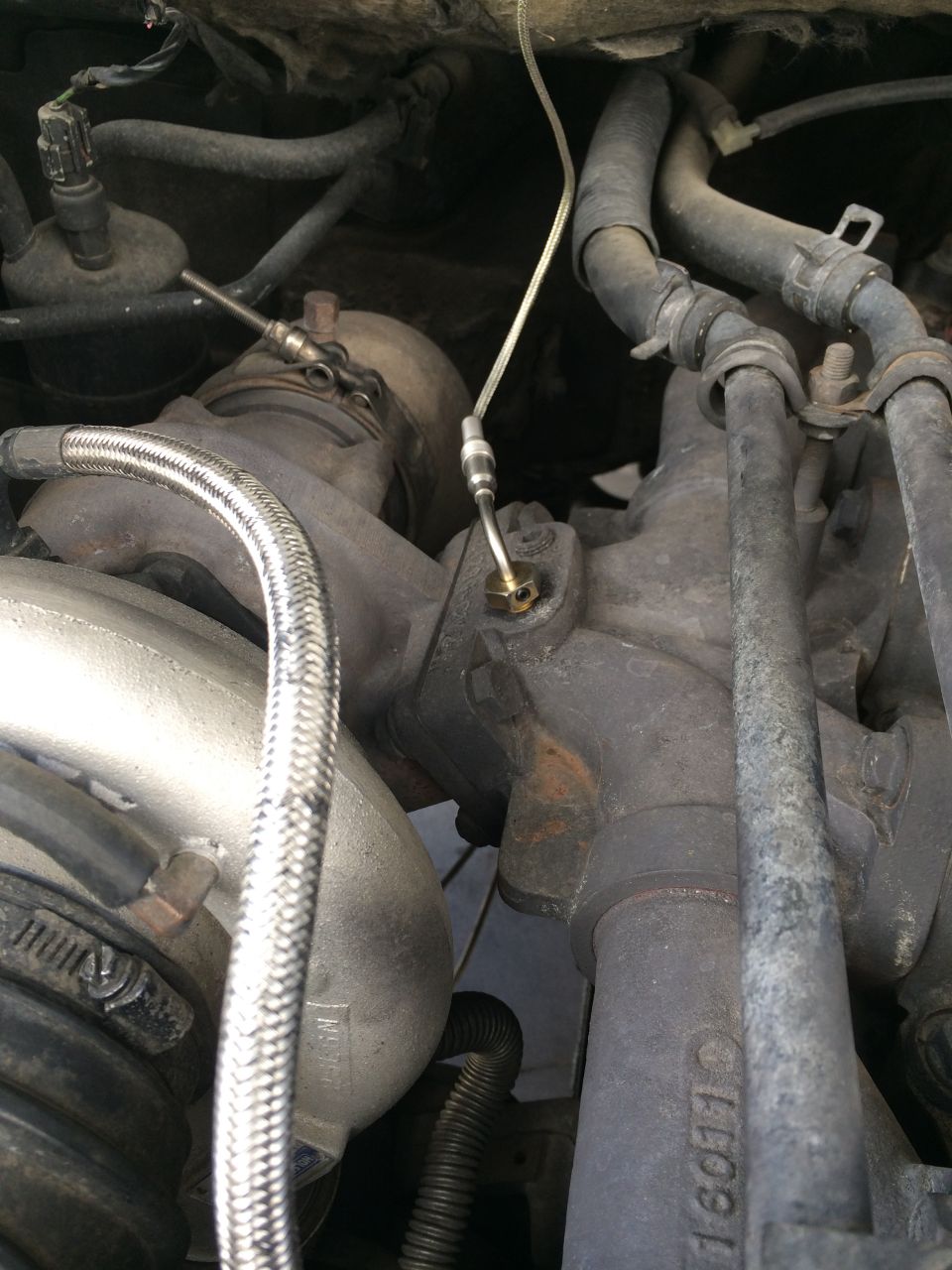 Close-up of turbocharger housing with braided hose and sensor line attached