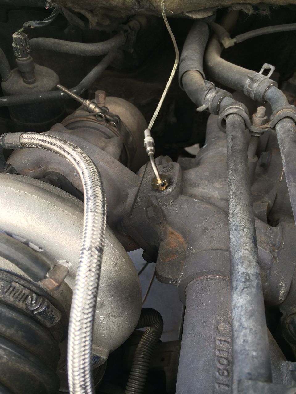 Close-up of a turbocharger with metal braided hose and rubber hoses connected