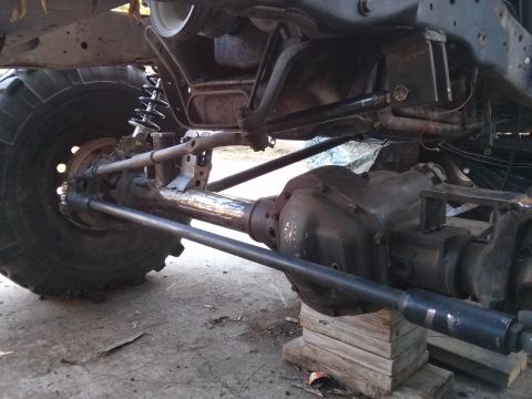 1986 Ford Bronco - Close-up view of the undercarriage of a heavily modified vehicle, focusing on the drivetrain and suspension.