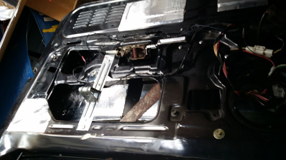 Car door interior with window mechanism and wiring exposed, showing soundproofing material