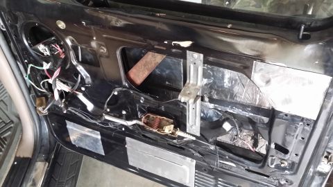 1994 Ford Bronco - The interior of a car door is shown with soundproofing material and exposed wiring, revealing its internal components.