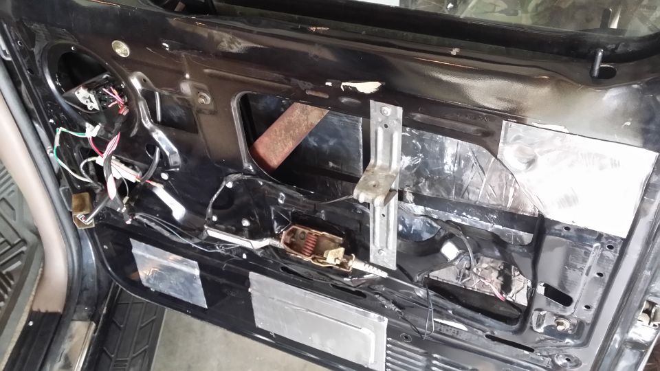 Car door interior with soundproofing material and exposed wiring