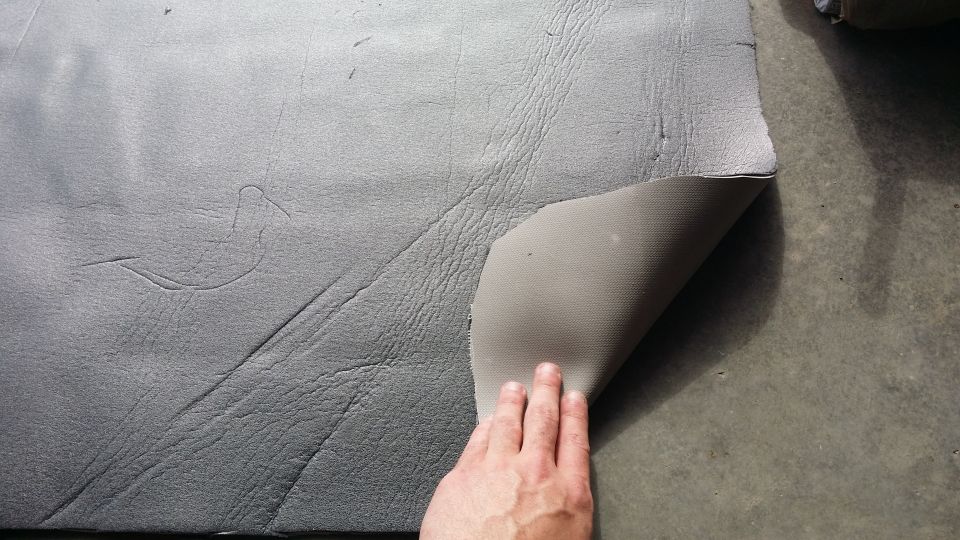 hand peeling back sound deadening material from floor