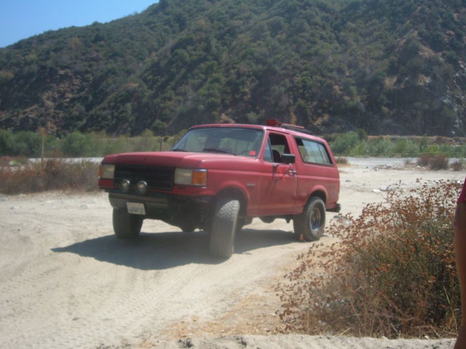 red SUV with off-road tires on a dirt road, mountains in background