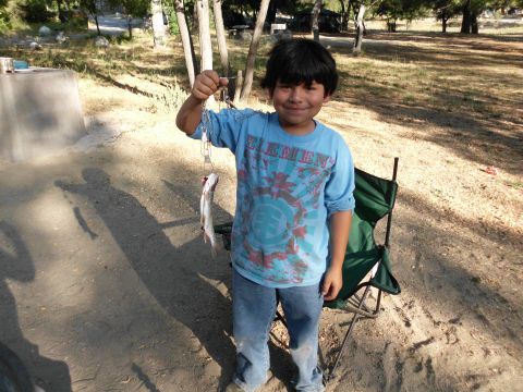 1988 Ford Bronco - A young boy proudly displays a freshly caught fish while standing outdoors.