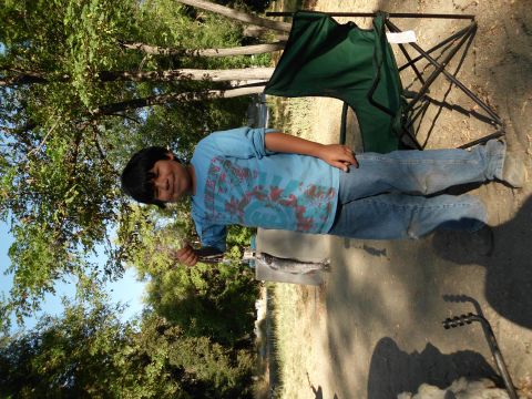 1988 Ford Bronco - A boy proudly displays a fish he caught, with a camping chair nearby in a wooded area.