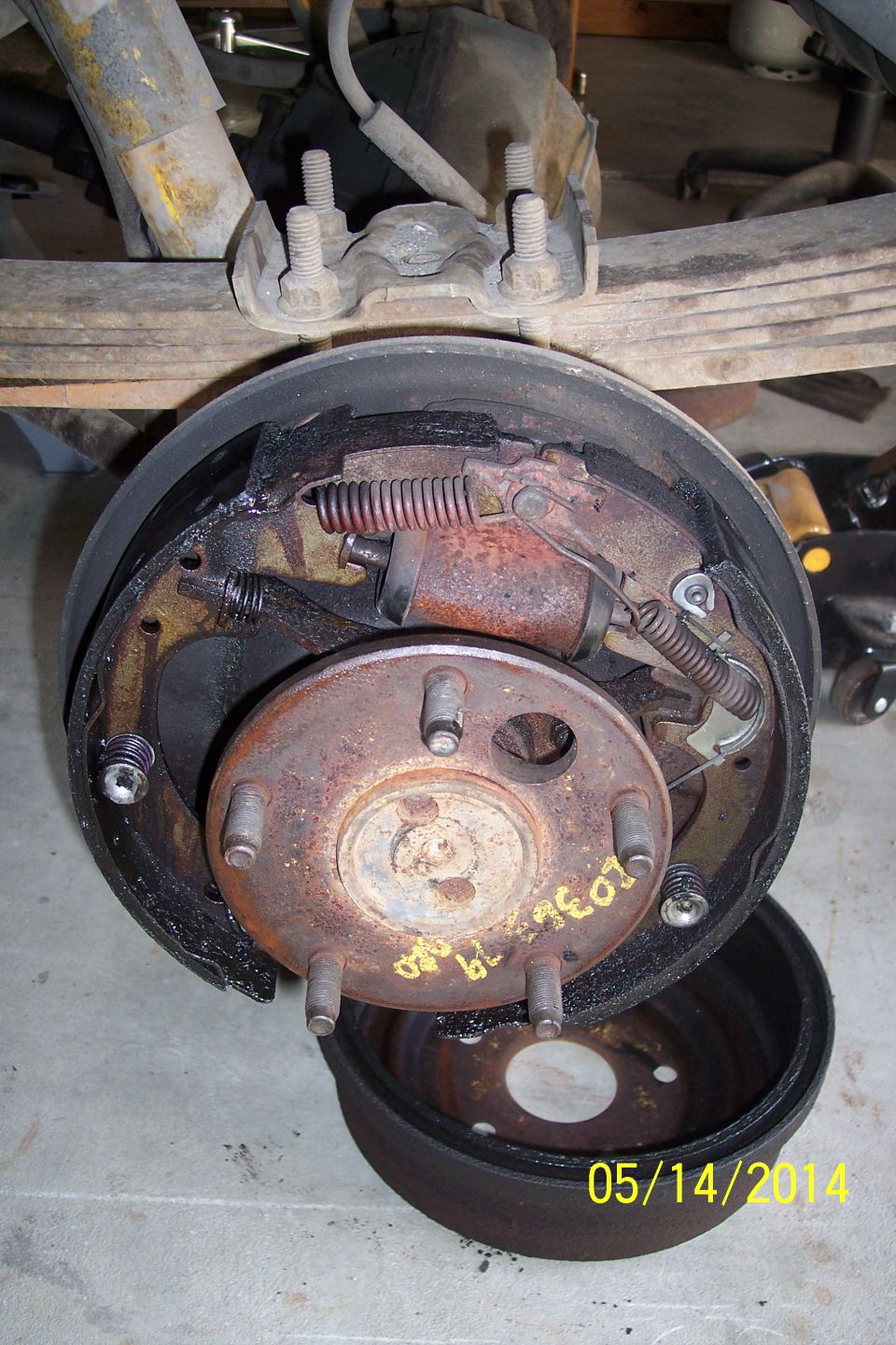 Rear drum brake assembly with brake shoes, springs, and wheel cylinder. Drum is removed