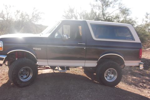 1992 Ford Bronco - This Ford Bronco is parked on a dirt lot with desert brush in the background.
