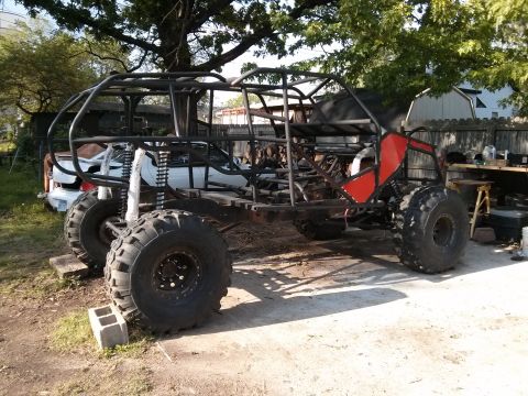 1986 Ford Bronco - This custom-built buggy frame, large off-road tires and red body panels, is seen in a yard setting.