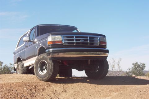 1992 Ford Bronco - This dark SUV with a white top is shown from the front 3/4 angle on a dirt hill.