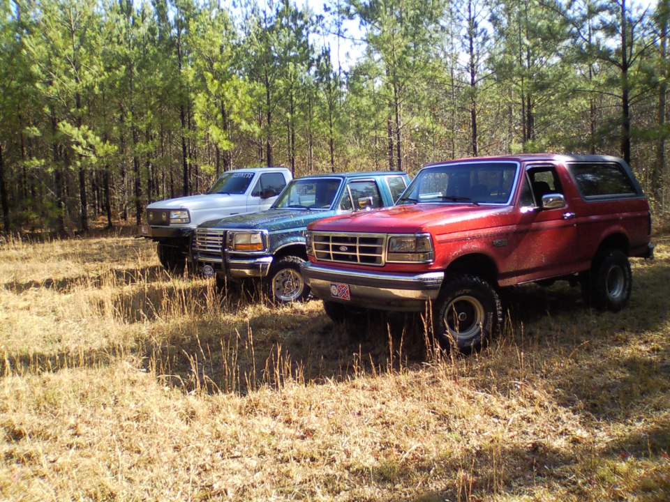 Red 1992 Ford Bronco parked in a field, viewed from the front three-quarter angle